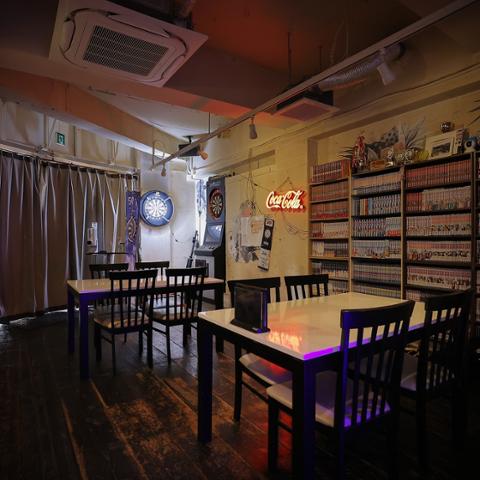 和やかふぇ こころひとつの店内。ダーツボードとテーブル席、本棚が並ぶ